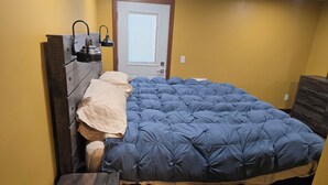 A bedroom with a bed, a dresser, a nightstand, and a door with a window. - Black Hills Barking Bunkhouse - Remodeled bldg with all amenities and 3 RV sites (Belle Fourche)