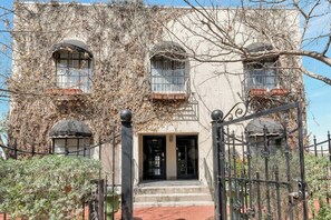 A building with a wrought iron gate, a set of steps leading to a door, and a balcony with a railing. - Downtown Fort Worth Chic Apartment (Fort Worth)