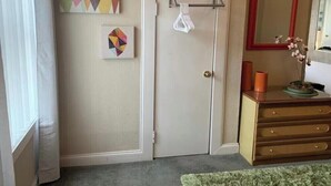 Ein Zimmer mit Tür, Spiegel, Kommode und Bildern an der Wand.
