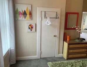 A room with a door, a mirror, a dresser, and artwork on the wall. - Downtown Fort Worth Chic Apartment (Fort Worth)