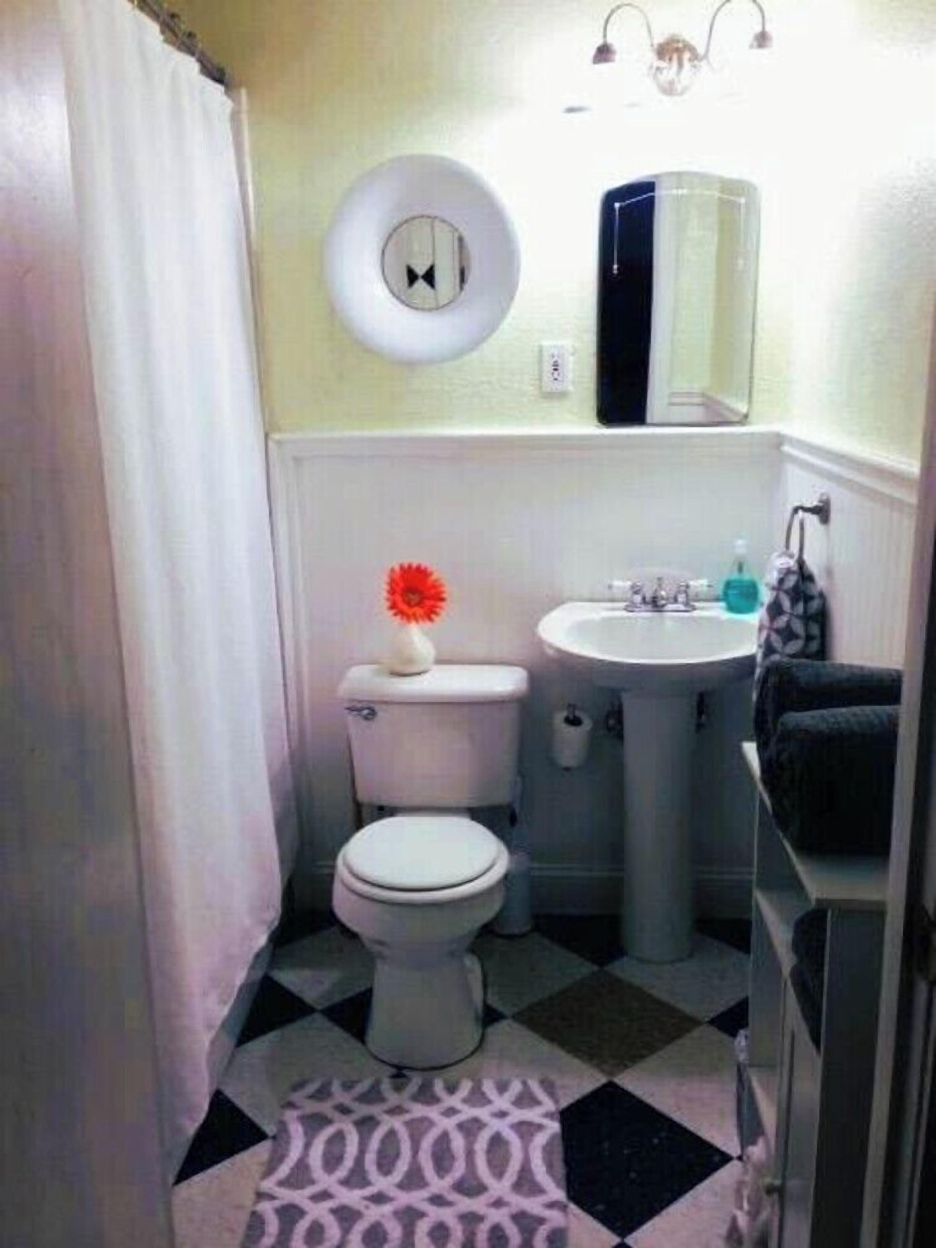 A bathroom with a toilet, sink, and mirror.