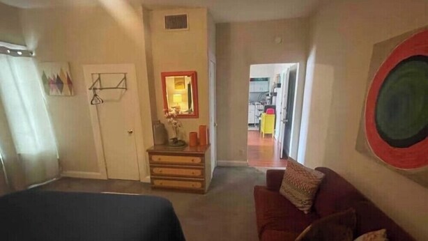 Ein Wohnzimmer mit einer Couch, einem kleinen Tisch mit einer Lampe und einer Tür zu einem anderen Raum.
