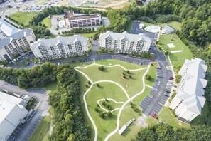 Ein mehrstöckiges Wohngebäude mit Innenhof, Parkplätzen und umliegender Bepflanzung.