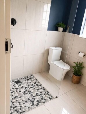 A bathroom with a shower, toilet, and a small potted plant. - 2 Bed Garden Cottage |Pool| Garden (Sandton)