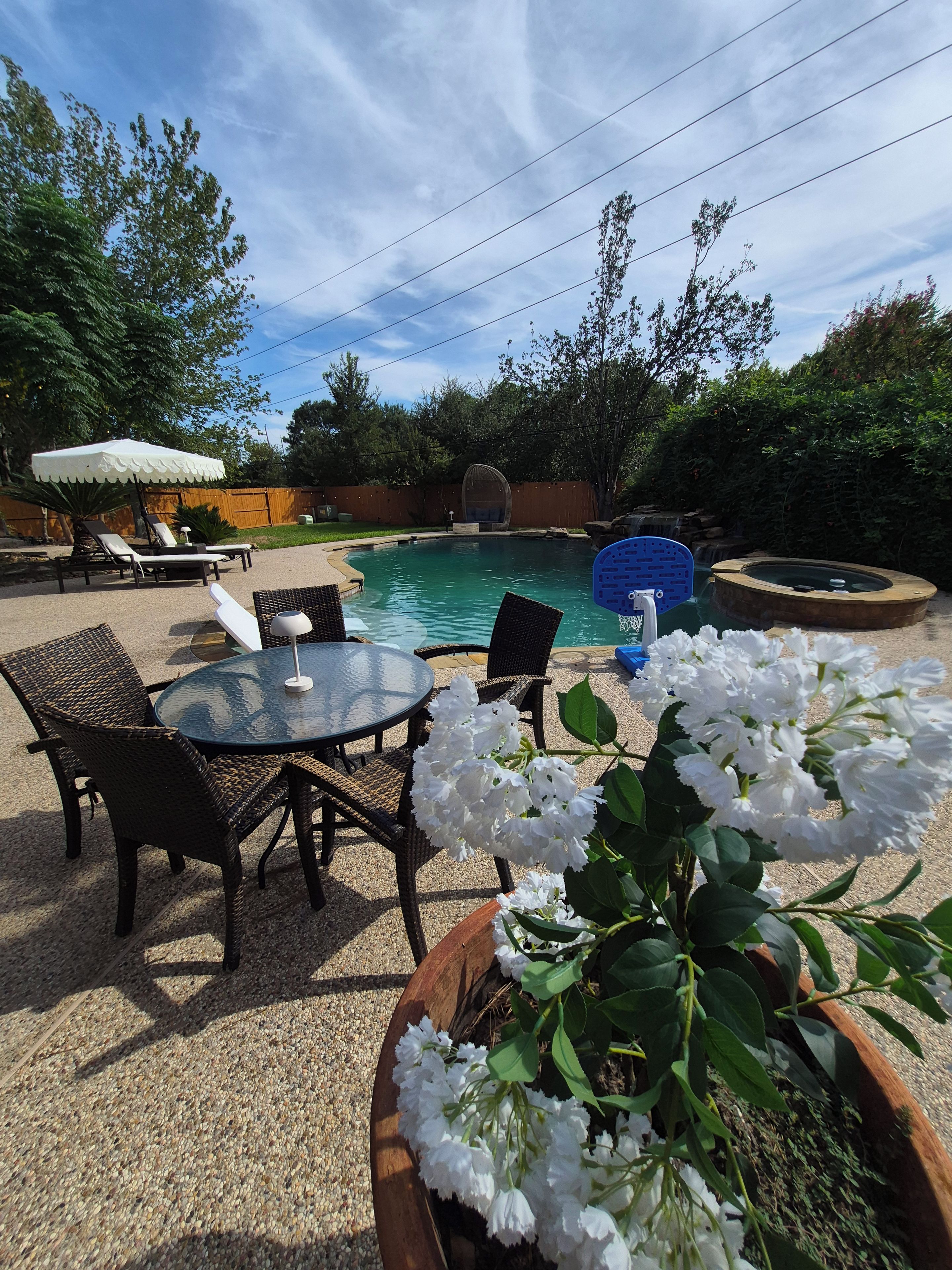 Un jardin avec une piscine, des chaises longues et une table avec des chaises.