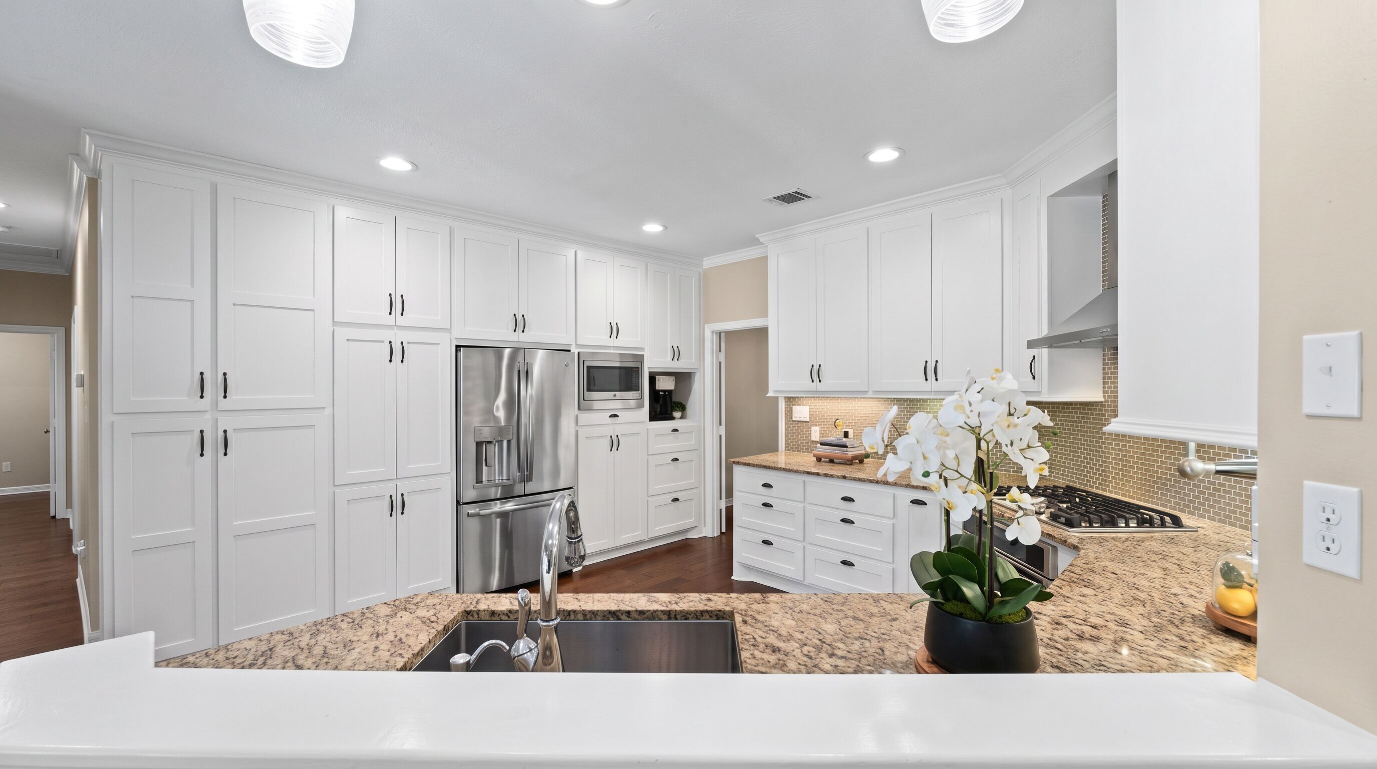 A modern kitchen with white cabinetry, stainless steel appliances, and a granite countertop.