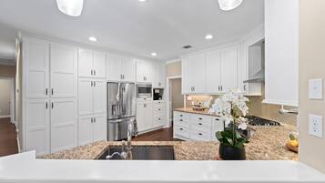 A modern kitchen with white cabinetry, stainless steel appliances, and a granite countertop.