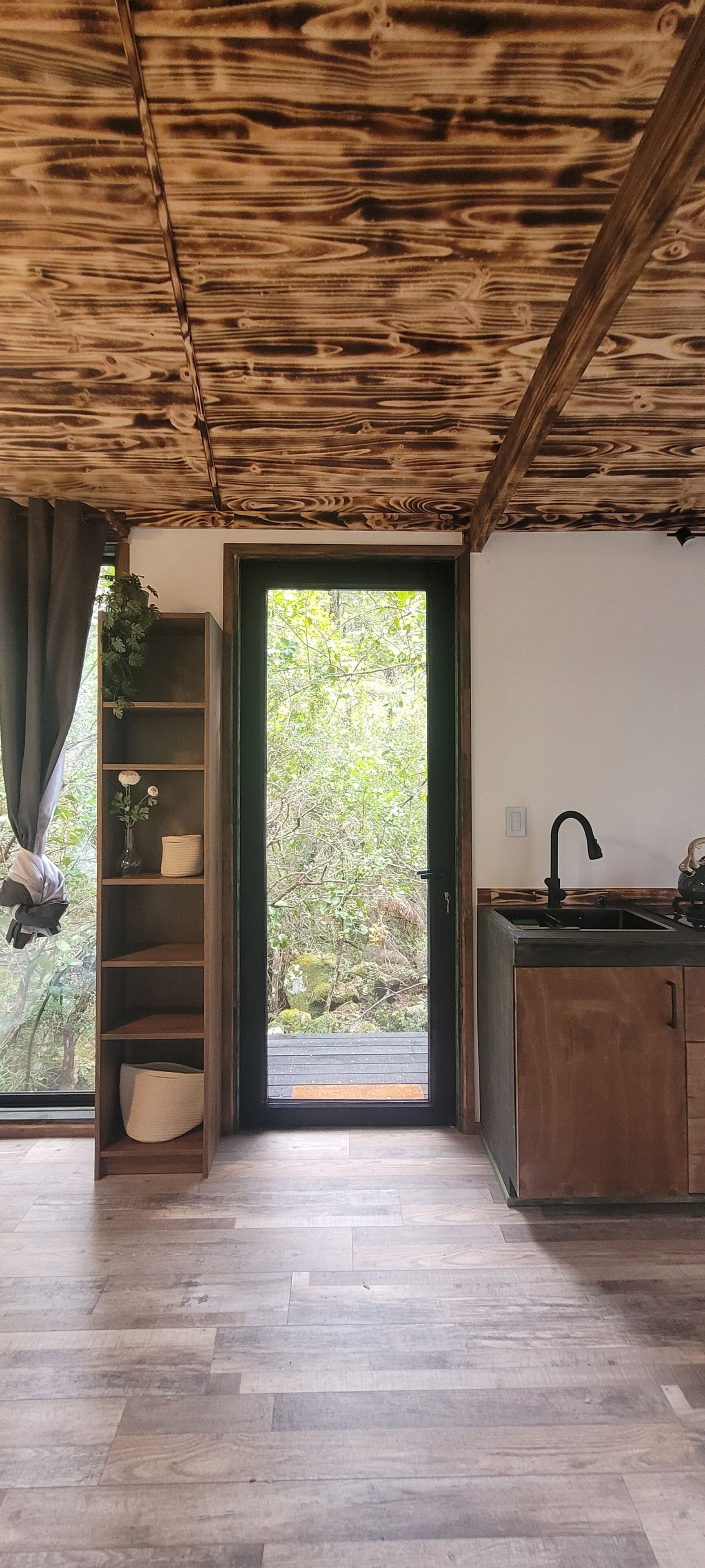 Un intérieur en bois donnant sur l’extérieur, une étagère intégrée et un coin cuisine.