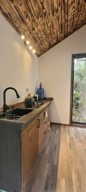 Eine moderne Küche mit Holzboden, einem großen Fenster und einem Wasserspender.