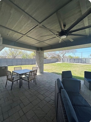 An outdoor patio with a table and chairs, a ceiling fan, and a view of a grassy yard. - Cozy 2 bedroom home close to downtown Frisco! Enjoy all that Frisco has to offer (Frisco)