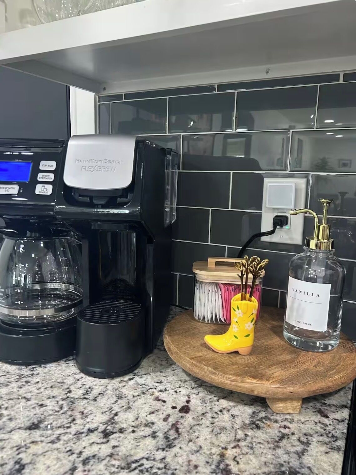 Een keukenblad met een koffiezetapparaat, een flesje vanille en een decoratieve gele laars.