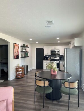 A modern kitchen with white cabinets, a black refrigerator, and a dining area with a round table and four chairs. - Cozy 2 bedroom home close to downtown Frisco! Enjoy all that Frisco has to offer (Frisco)