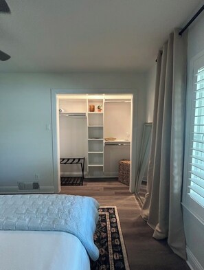 Ein Schlafzimmer mit einem Bett, einem begehbaren Kleiderschrank und einem Fenster mit Vorhängen.