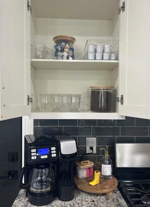 Eine Küche mit Kaffeemaschine, einem Fläschchen Vanilleextrakt und einem Holztisch.