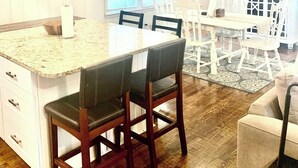 A kitchen with a central island, dining area with chairs, a clock, and a sign that reads 'Home Sweet Home.' - Near McLeod & Downtown · Sleeps 6 · Free WiFi (Florence)
