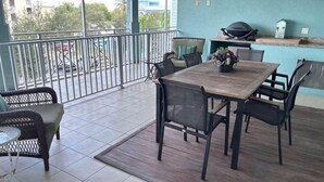 Un balcón con una mesa y sillas, una parrilla y vistas al exterior.
