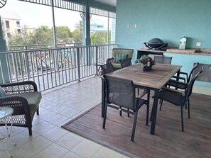 Ein Balkon mit Esstisch und Stühlen, einem Grill und Blick ins Freie.