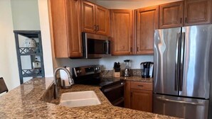 Una cocina con encimeras de granito, electrodomésticos de acero inoxidable, armarios de madera y microondas integrado.
