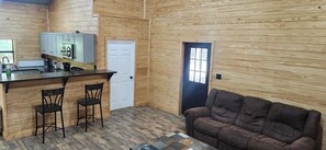 A compact kitchen with a bar area, a door, and a seating area with a couch.