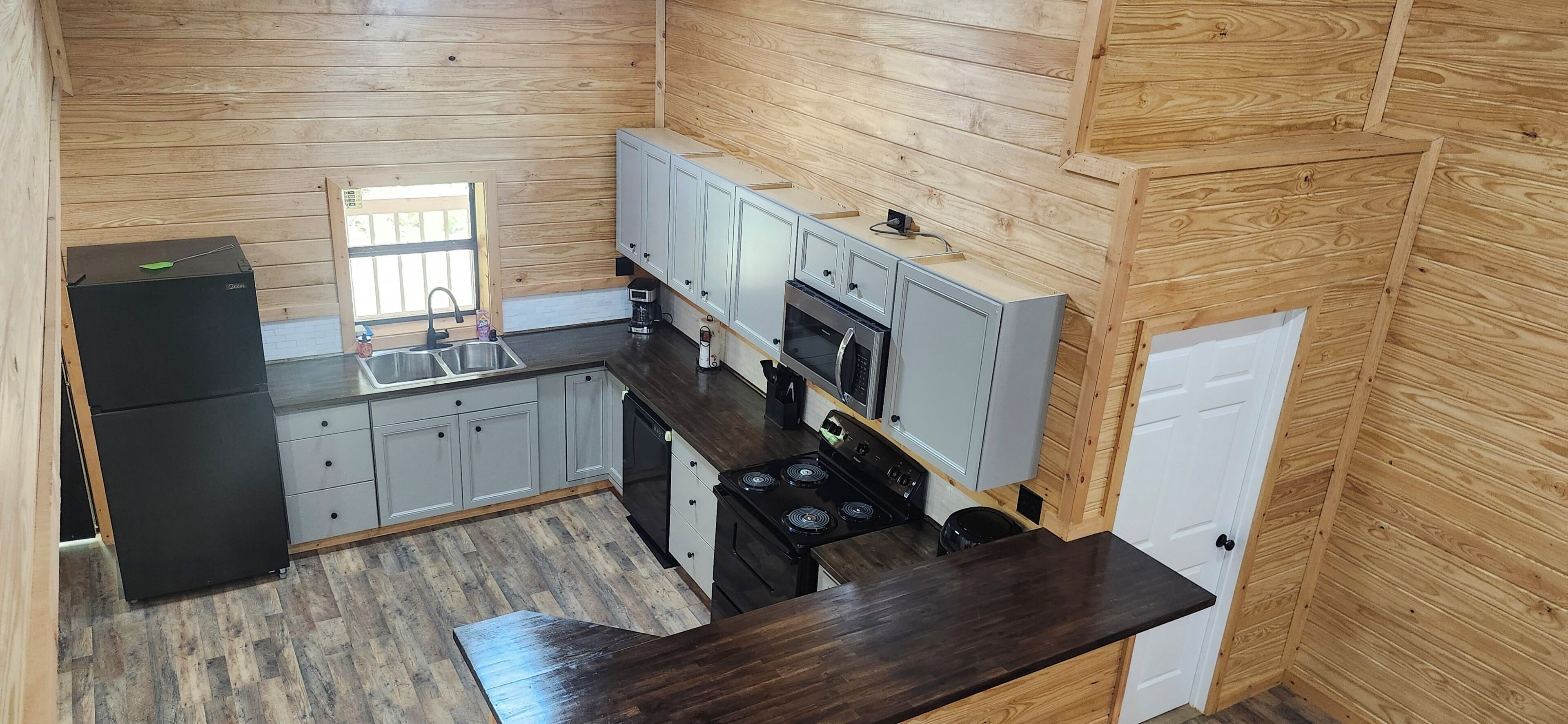 A compact kitchen with a refrigerator, sink, stove, and cabinets.
