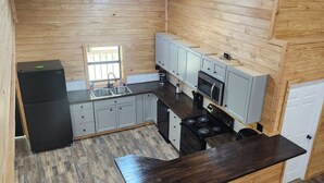 A compact kitchen with a refrigerator, sink, stove, and cabinets. - Sam Rayburn Getaway (Sam Rayburn)