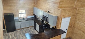 A compact kitchen with a refrigerator, sink, stove, and cabinets.