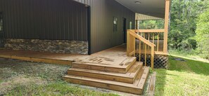 A wooden deck leading to a house with a stone accent wall.