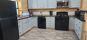 A kitchen with white cabinets, a black refrigerator, a microwave, a stove, and a dishwasher.