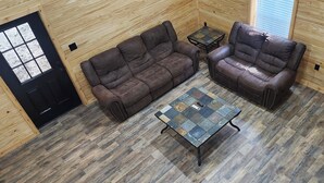 A room with two leather sofas, a small table, and a wooden floor. - Sam Rayburn Getaway (Sam Rayburn)