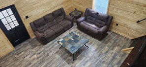 A room with two leather sofas, a small table, and a wooden floor.