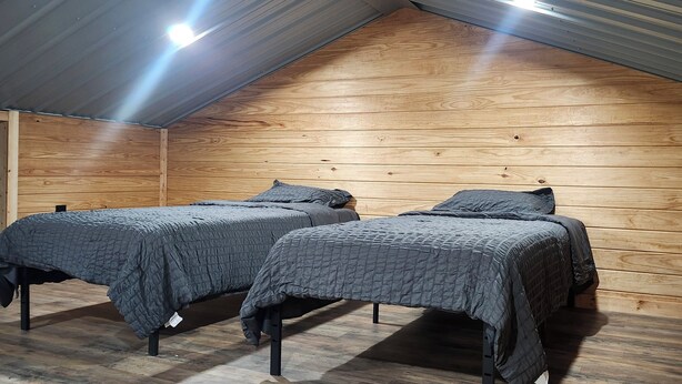 A room with two beds, wooden walls, and a sloped ceiling. - Sam Rayburn Getaway (Sam Rayburn)