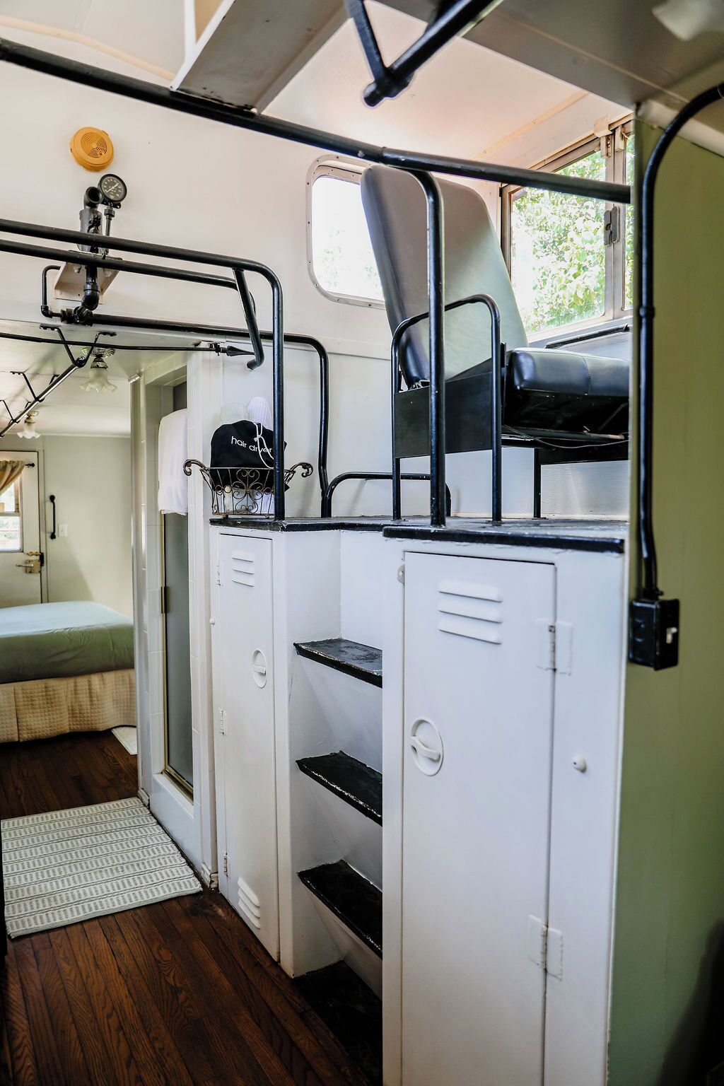 Een compact, goed verlicht interieur met een stapelbed, een kleine keukenhoek en een raam dat natuurlijk licht toelaat.