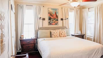 Hotelkamer met een bed, nachtkastje, dressoir, plafondventilator en een schilderij van een canyon.