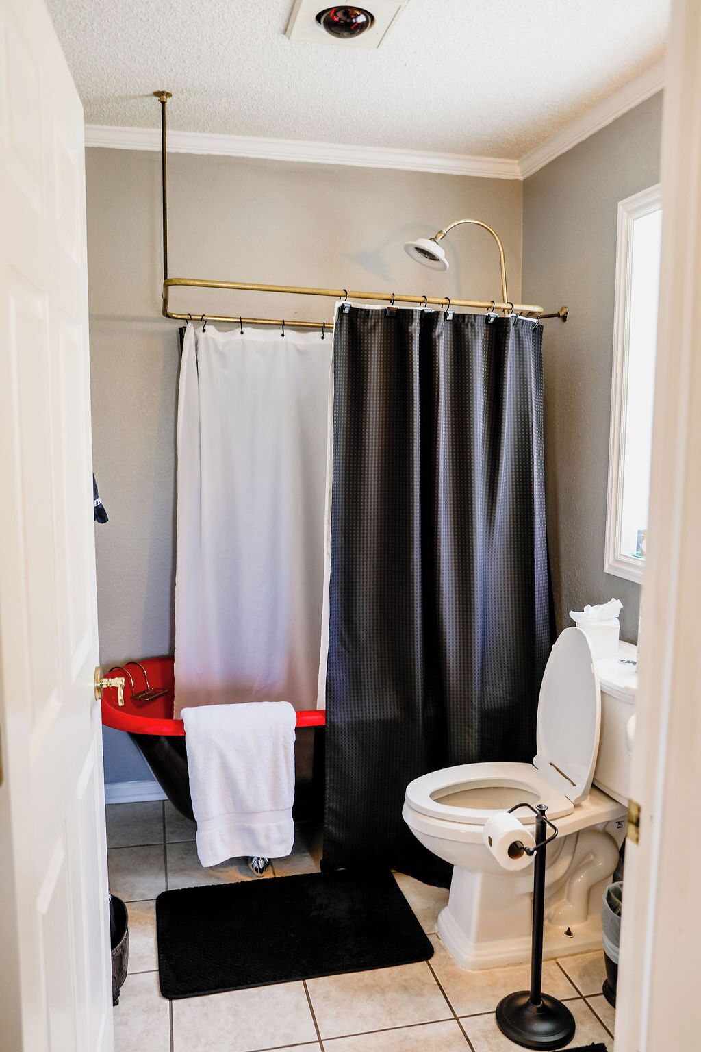 A bathroom with a toilet, a sink, a shower curtain, and a towel rack.