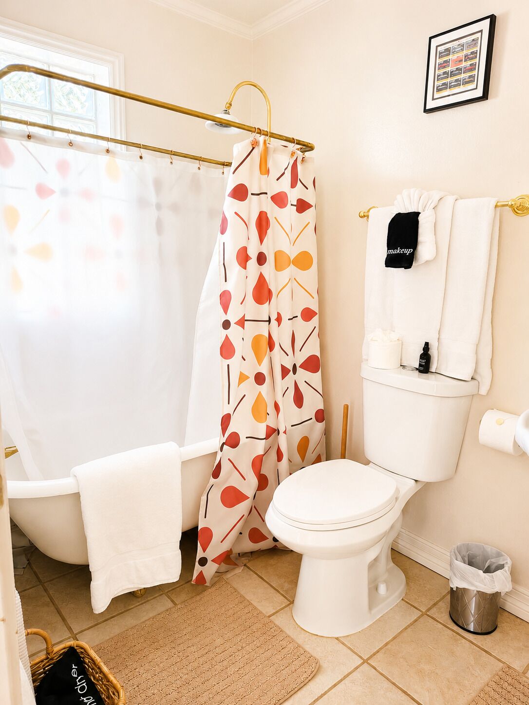 A bathroom with a bathtub, toilet, and a shower curtain with a leaf pattern.