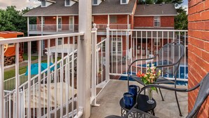 A balcony with a pool, outdoor furniture, and a view of a two-story house. - The Woodrow House (Lubbock)