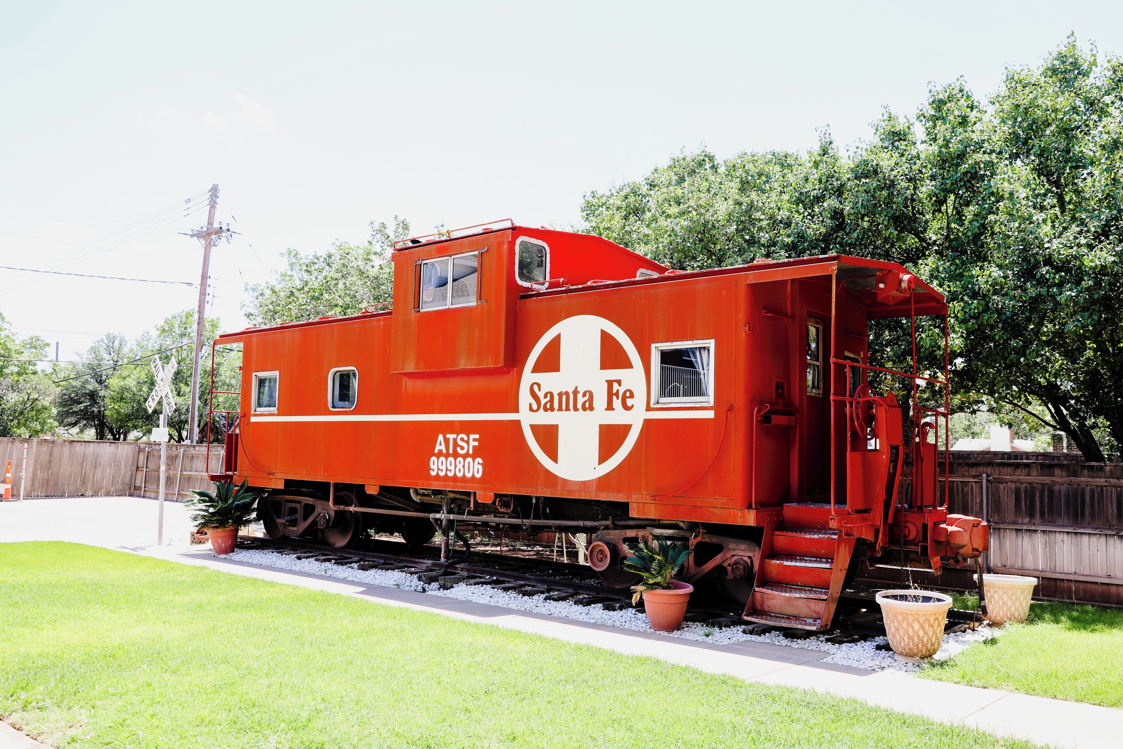 A red Santa Fe caboose with the number ATSF 999806 parked on tracks.