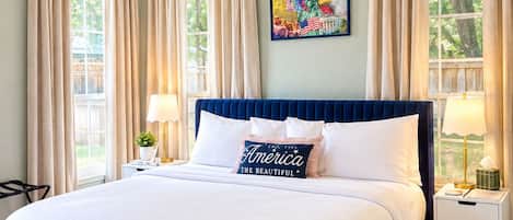 A bedroom with a bed, two bedside tables, a ceiling fan, and a window with curtains.