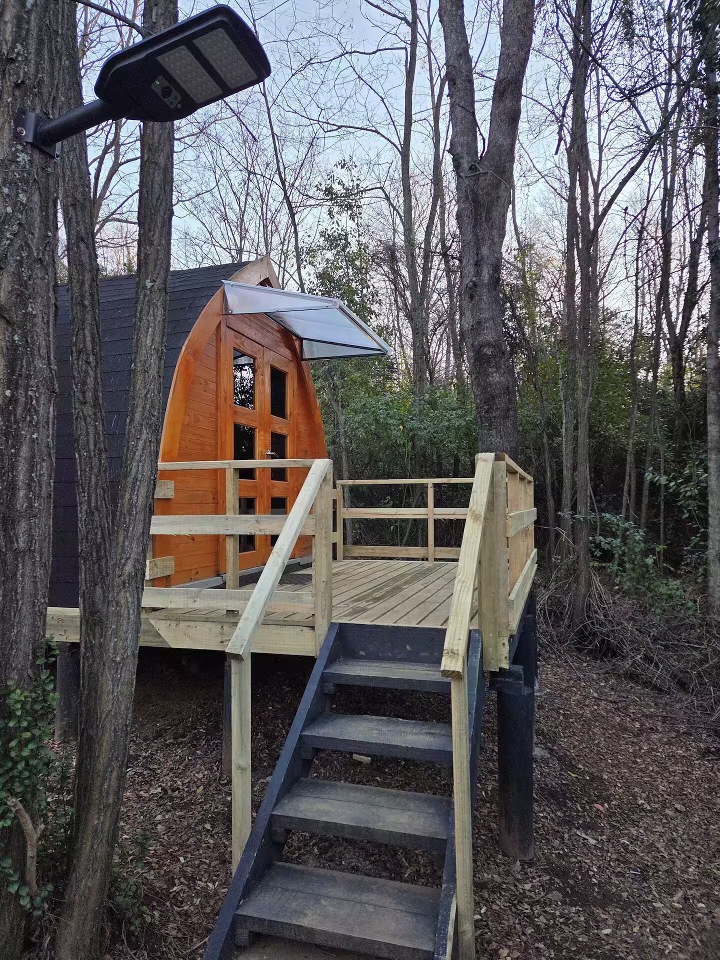 A wooden deck with a staircase leading to a cabin-like structure surrounded by trees.