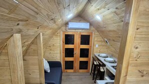 Une petite pièce en bois comprenant un lit, une petite table et un coin cuisine.