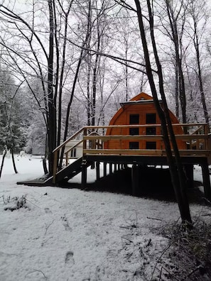 A wooden cabin on stilts in a snowy forest.