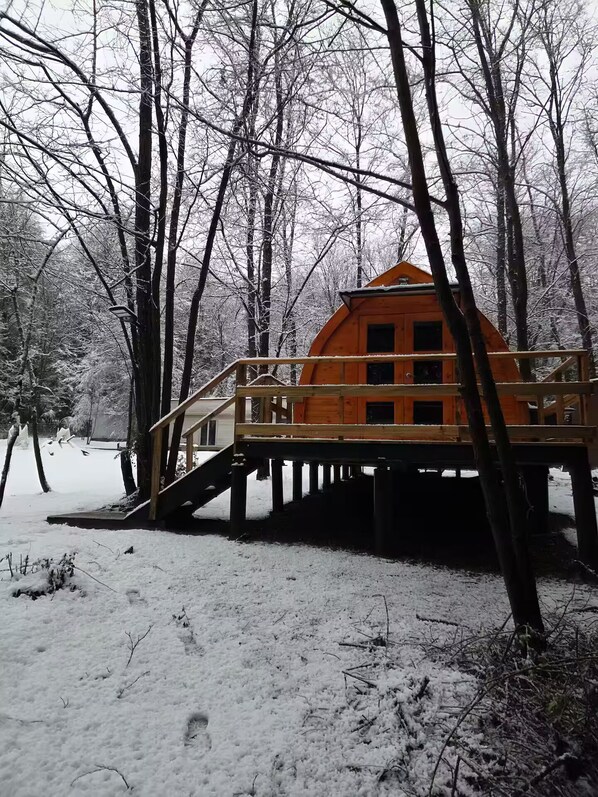 A wooden cabin on stilts in a snowy forest.