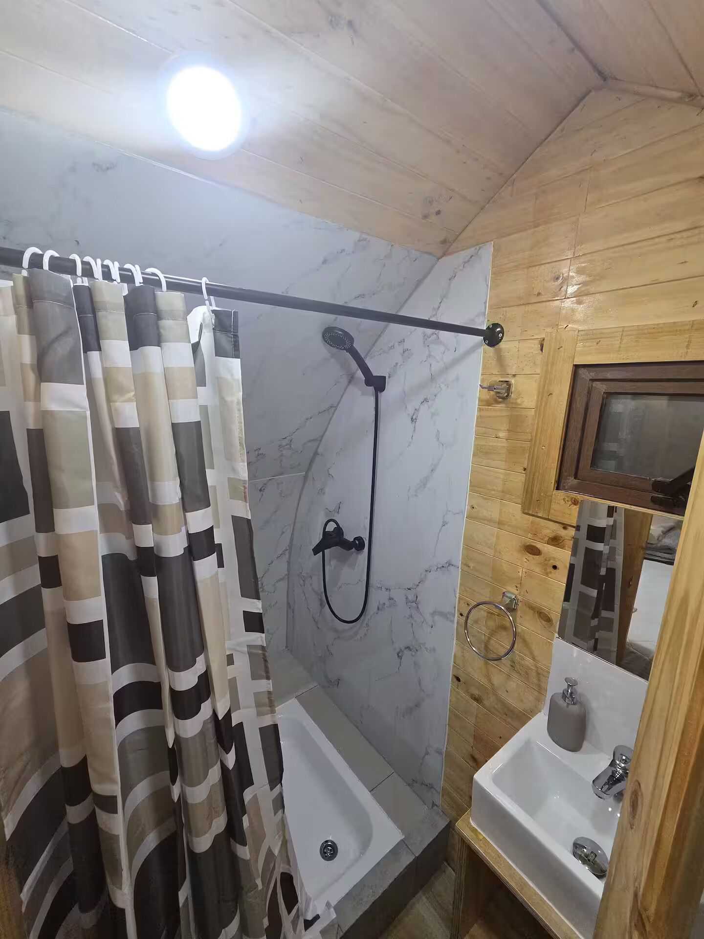 A bathroom with a shower, a sink, and a mirror.