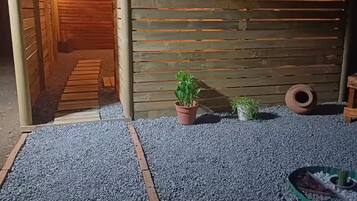 Una cerca de madera con tablones horizontales, un camino de grava y plantas en macetas.