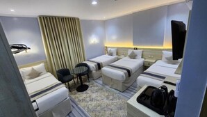 Habitación de hotel con dos camas individuales, una mesita pequeña, una silla, un escritorio con una computadora y un espejo grande.