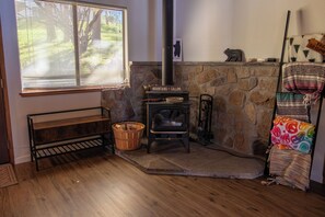 A cozy room with a stone fireplace, a bench, a basket, and a colorful blanket. - A magical cabin located in -The "Gateway to Yosemite" (Groveland)