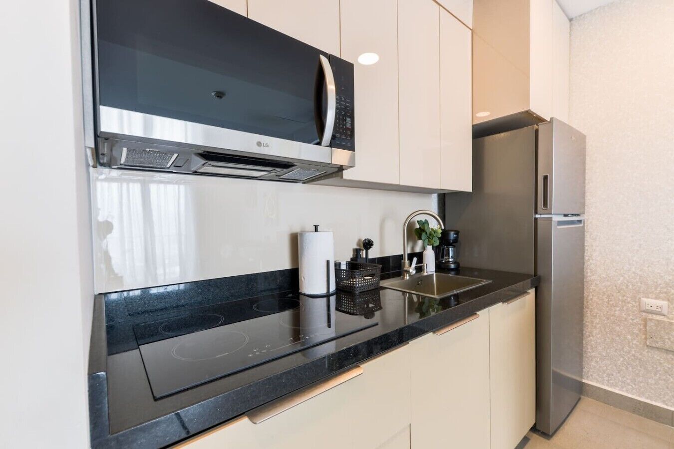 A modern kitchen with a microwave, stove, sink, and refrigerator.