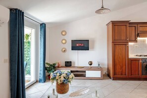 A modern kitchen with wooden cabinets, a flat-screen TV mounted on the wall, and a dining area with a wooden table and chairs. - Sardinia. Cozy apartment in the city center with a balcony and panoramic views. Serves 6. (Tortolì)