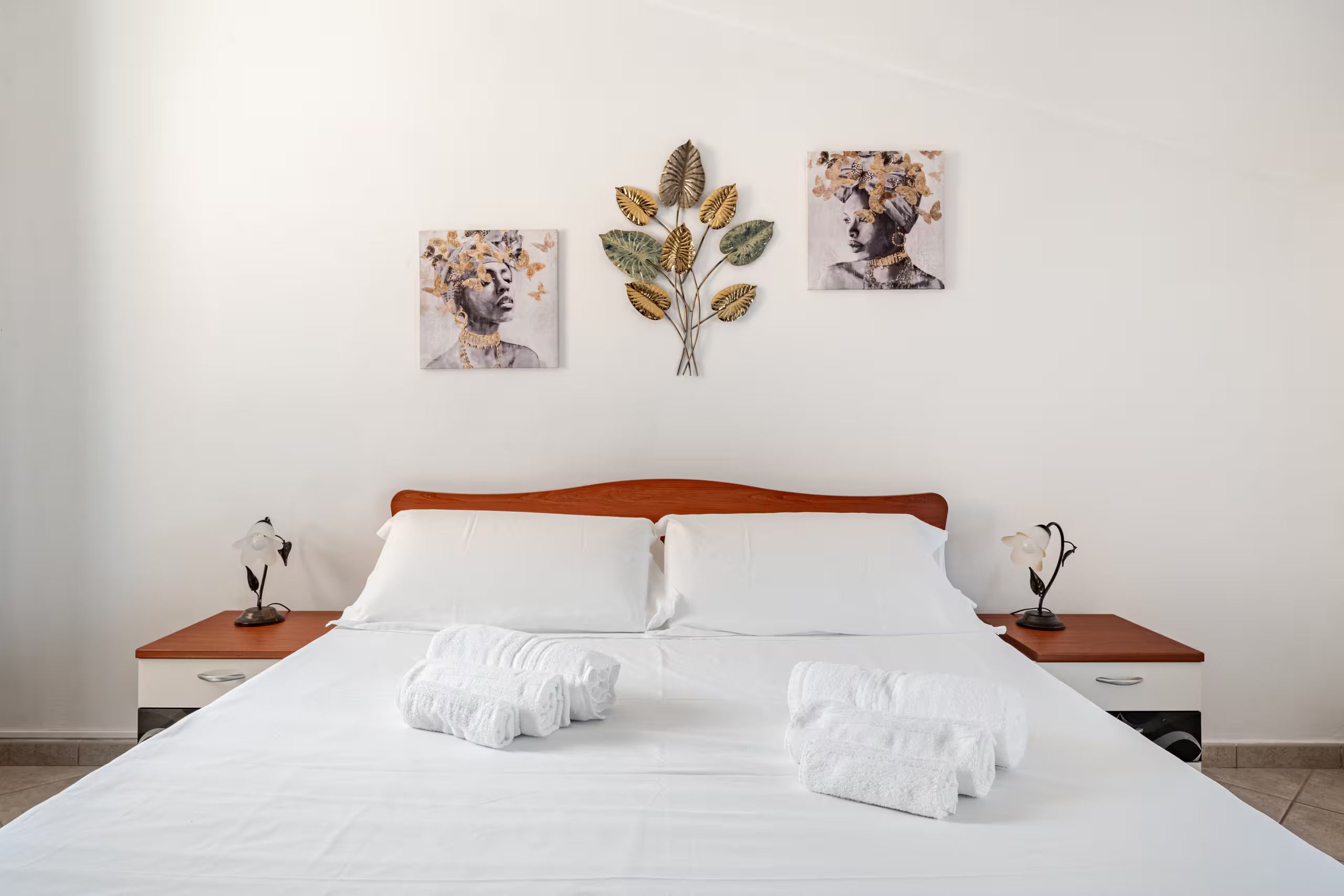 Una habitación de hotel con una cama grande, dos mesitas de noche y tres obras de arte colgadas en la pared.