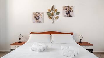 Una habitación de hotel con una cama grande, dos mesitas de noche y tres obras de arte colgadas en la pared.